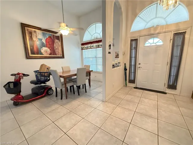 Foyer entrance featuring ceiling fan with notable chandelier, light tile patterned flooring, and high vaulted ceiling