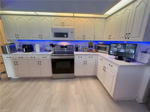 Kitchen with light hardwood / wood-style flooring, white cabinets, and stainless steel electric range