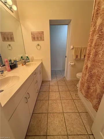 3rd Full/walkthrough bathroom featuring tile patterned floors, shower / tub combo with curtain, vanity, and toilet