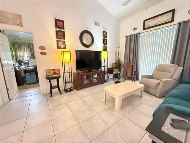 Living room with light tile patterned flooring and vaulted ceiling.  Door way on left side of picture is to enter the Master Suite.