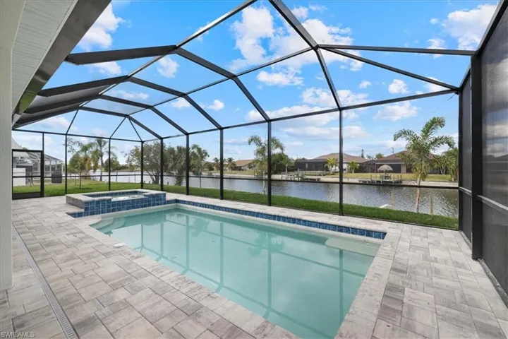 View of pool with a sunroom, a water view, a lanai, a patio area, and a pool with connected hot tub