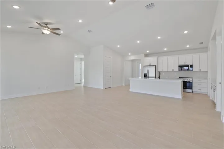 Unfurnished living room with recessed lighting, wood finish floors, a ceiling fan, and lofted ceiling