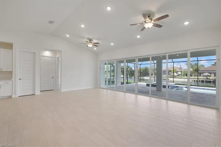 Living room featuring 24 foot slider, recessed lighting, lofted ceiling, ceiling fan, and wood tiled floors