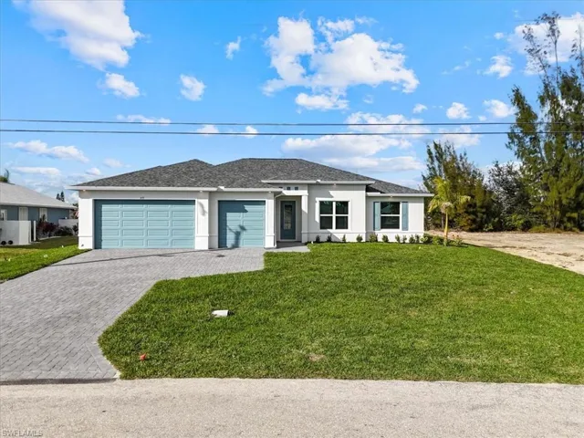 Prairie-style house with decorative driveway, stucco siding, a front yard, and an attached garage