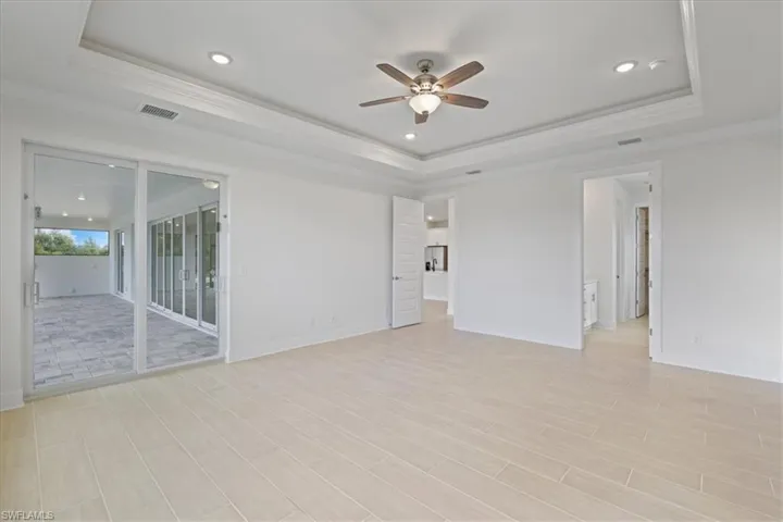 Empty room with ornamental molding, recessed lighting, ceiling fan, a raised ceiling, and wood tiled floors