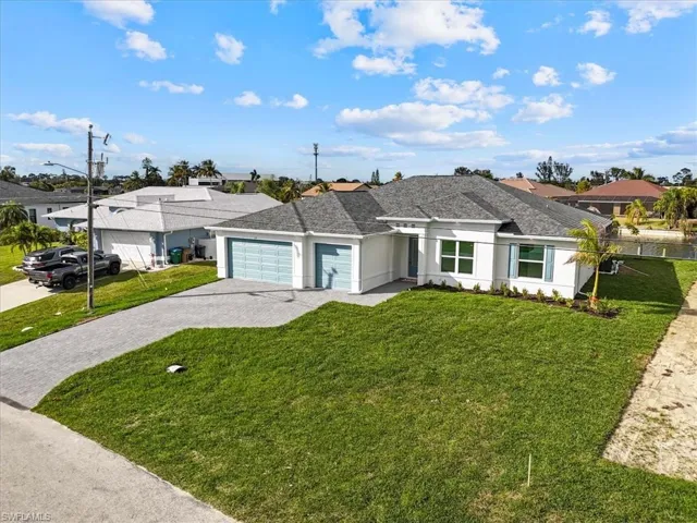 View of front of house featuring decorative driveway, an attached garage, a front lawn, and roof with shingles