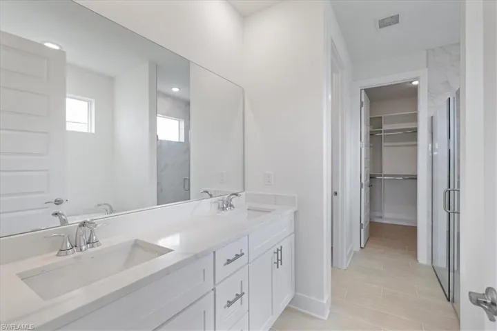 Bathroom with a spacious closet, a marble finish shower, and double vanity