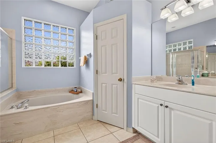 Full bathroom featuring a shower stall, vanity, a bath, and light tile patterned floors