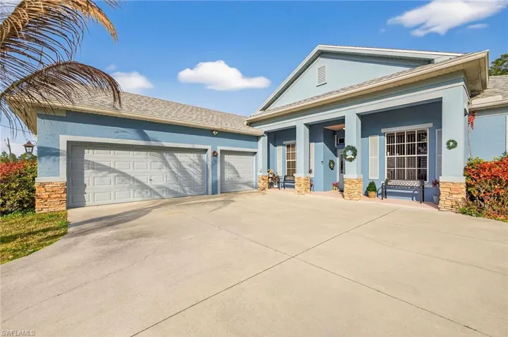 View of front facade with stucco siding, concrete driveway, stone siding, a porch, and an attached garage
