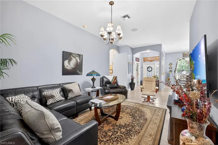 Living area with arched walkways, hanging lights, and light tile patterned floors