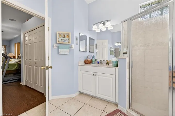 Full bathroom featuring a stall shower, light tile patterned flooring, and vanity