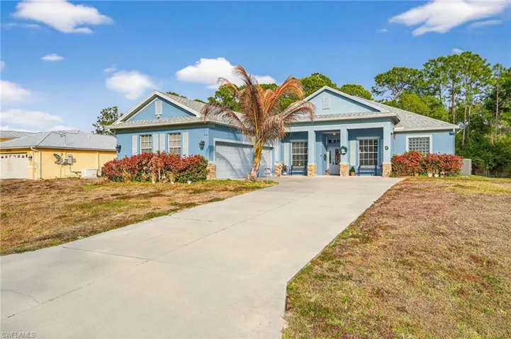 View of front of house with a front lawn, stucco siding, driveway, and a garage