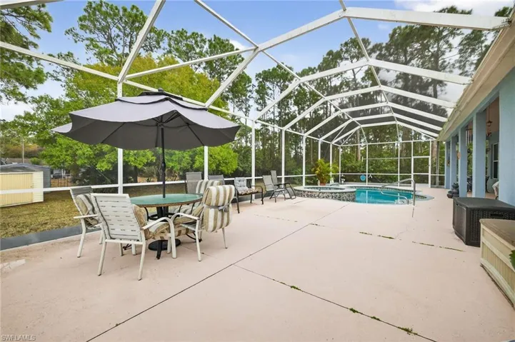 Integrated pool / spa with a sunroom, a patio, outdoor dining space, and glass enclosure