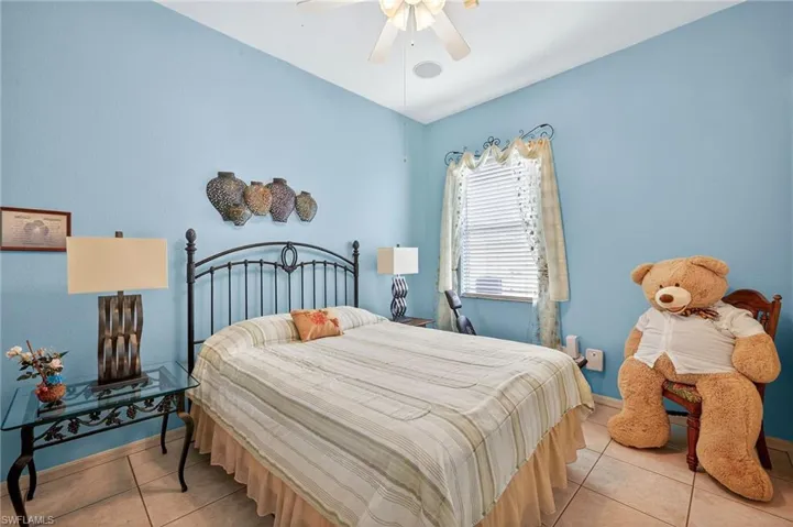 Tiled bedroom featuring ceiling fan and baseboards