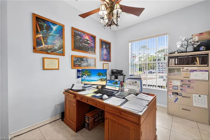 Office space with a ceiling fan and light tile patterned flooring