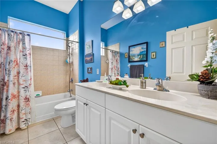 Bathroom featuring double vanity, shower / bath combo, and light tile patterned floors