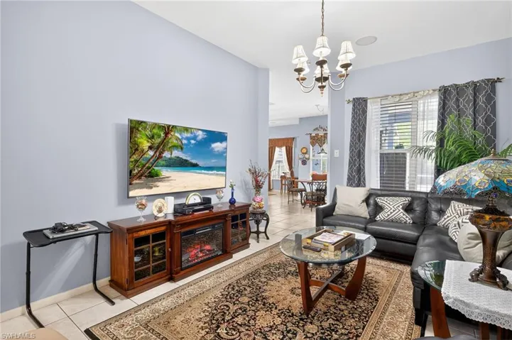 Living room with light tile patterned flooring and suspended lighting