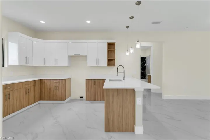 Kitchen featuring white cabinets, hanging light fixtures, sink, and kitchen peninsula
