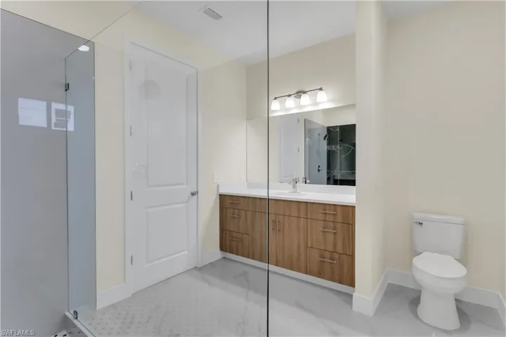 Bathroom with vanity, toilet, and a shower with door