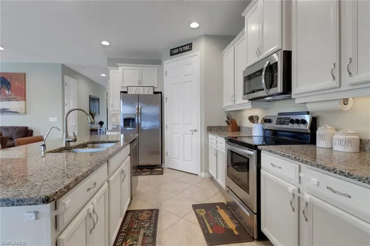 Kitchen featuring appliances with stainless steel finishes, a sink, white cabinetry, light tile patterned floors, and recessed lighting