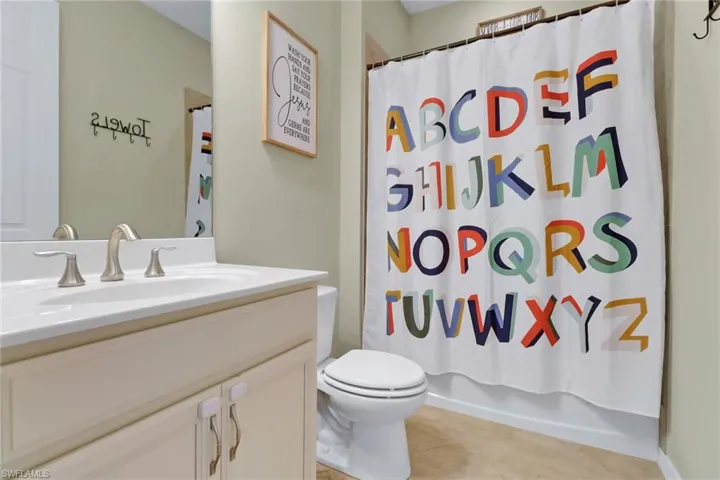 Full bath with tile patterned flooring, toilet, vanity, and shower / bath combo with shower curtain