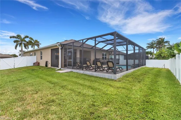 Rear view of property with a patio area, glass enclosure, stucco siding, and a gate