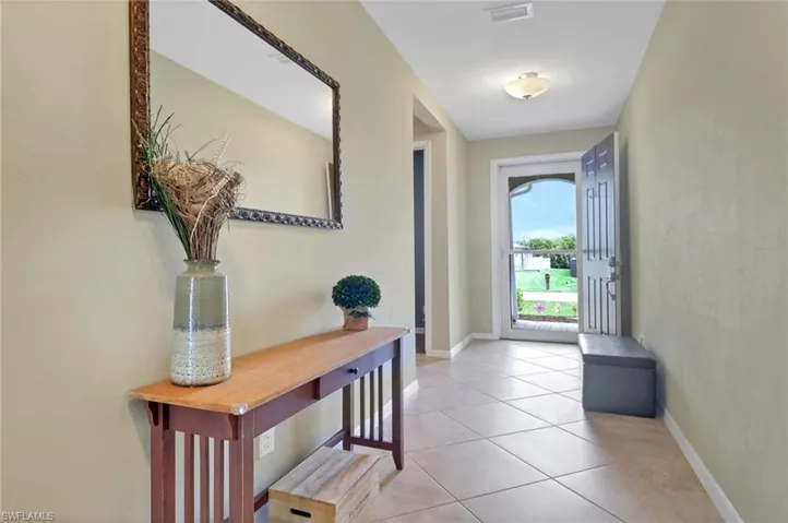 Doorway with light tile patterned flooring and baseboards