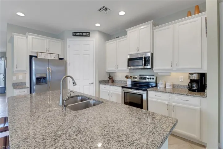 Kitchen featuring appliances with stainless steel finishes, a sink, white cabinetry, and recessed lighting