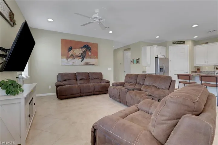 Living room featuring a ceiling fan, recessed lighting, light tile patterned flooring, and baseboards