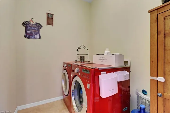 Laundry area with washing machine and dryer, tile patterned flooring, and baseboards