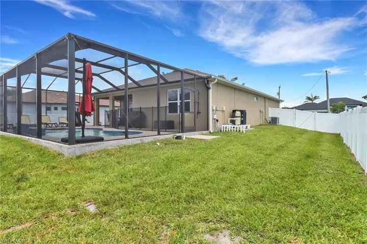 Back of property featuring cooling unit, stucco siding, glass enclosure, and a patio area