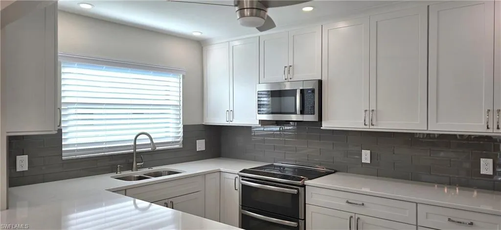 Stunning Kitchen Featuring Stainless Steel Appliances, Tall White Cabinets, light Quartz Stone Counters, Glass Tile   Backsplash, Ceiling Fan & Recessed Lighting