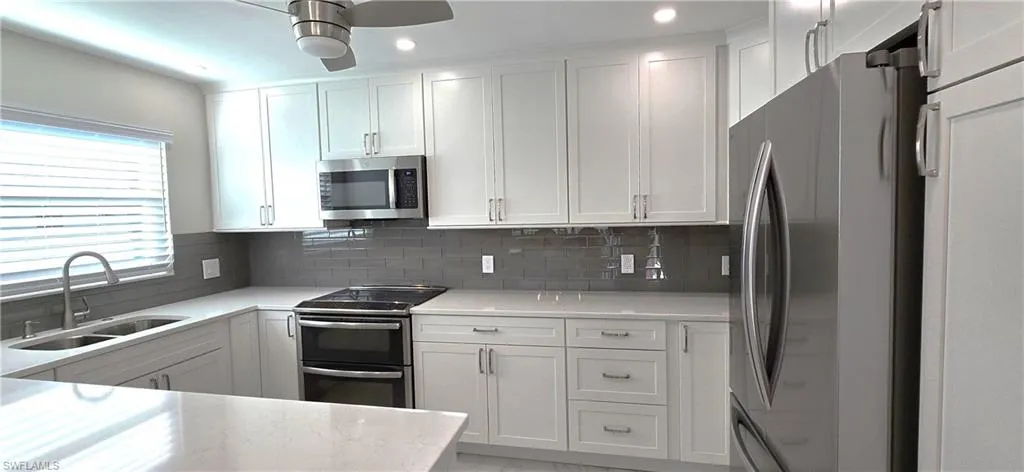 Kitchen with white cabinetry, appliances with stainless steel finishes, light stone countertops, tasteful backsplash, and recessed lighting