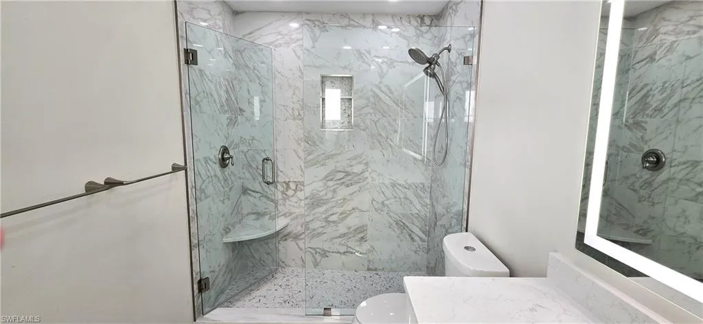 Full bathroom with a marble finish shower and vanity