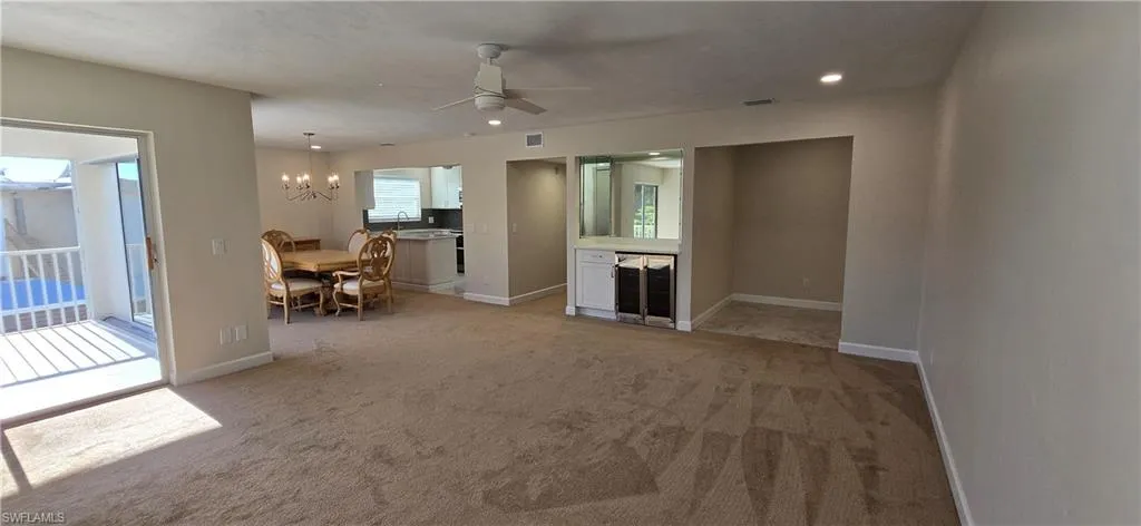 Living room with light carpet, plenty of natural light, a ceiling fan, a chandelier, and recessed lighting