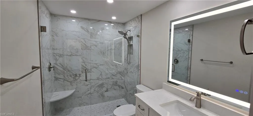 Bathroom featuring vanity, a marble finish shower, and recessed lighting