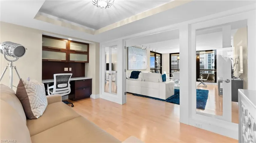 DEN with a tray ceiling, built in desk, and light hardwood / wood-style floors
