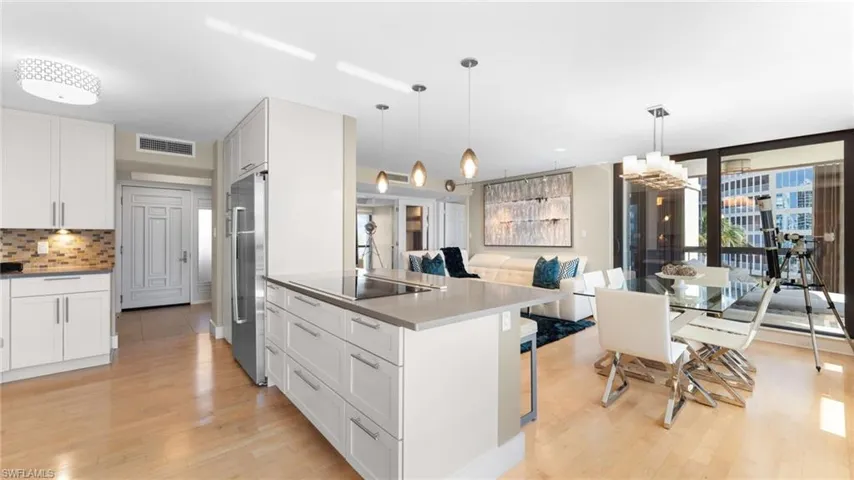 Kitchen featuring white cabinetry, decorative backsplash, light hardwood / wood-style floors, and hanging light fixtures