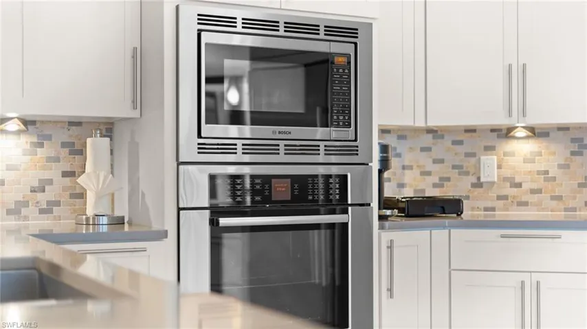 Kitchen with white cabinetry, stainless steel appliances, and tasteful backsplash