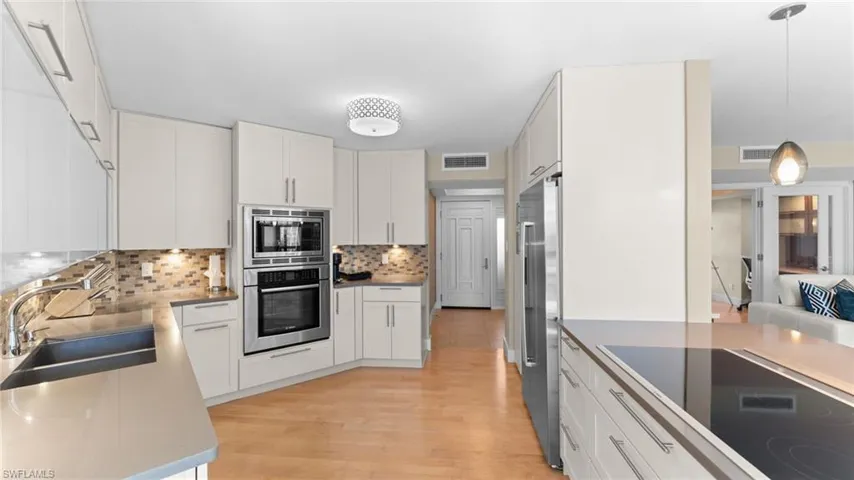 Kitchen featuring white cabinetry, appliances with stainless steel finishes, sink, and hanging light fixtures