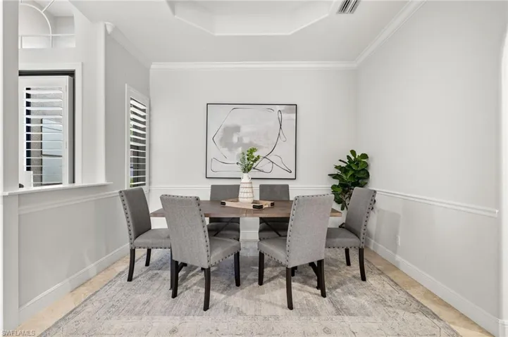Tiled dining room with crown molding and a raised ceiling