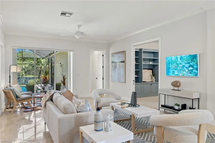 Tiled living room featuring built in features, crown molding, and ceiling fan