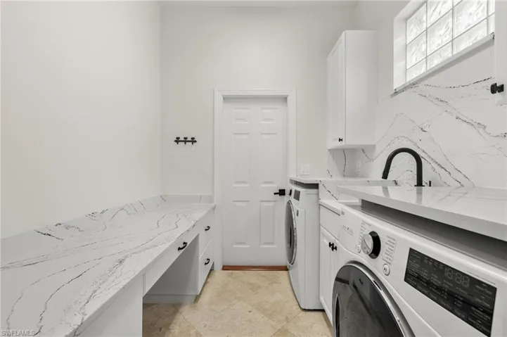 Laundry room featuring separate washer and dryer, cabinets, and light tile patterned floors