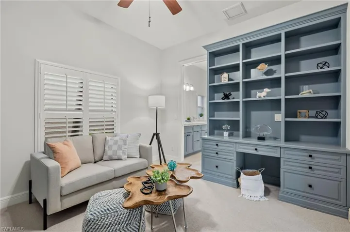 Living room featuring light carpet, ceiling fan, and built in desk