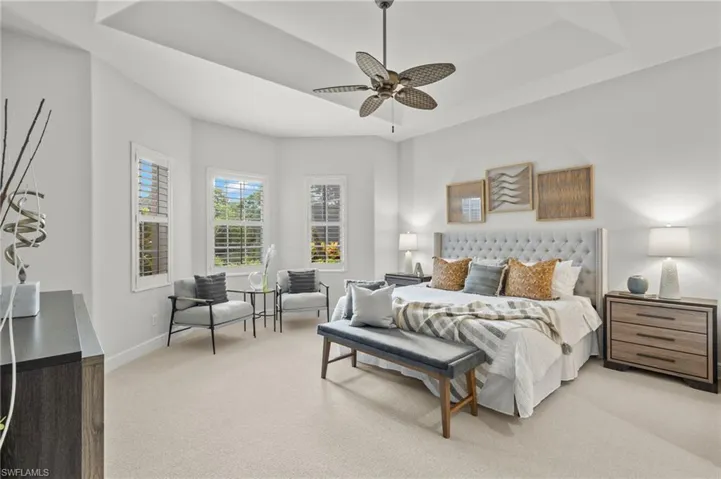 Carpeted bedroom with a raised ceiling and ceiling fan