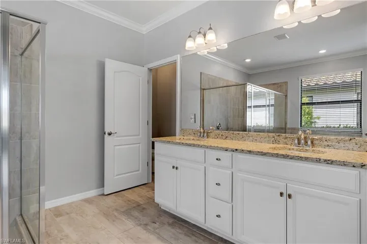 Full bathroom with a sink, double vanity, visible vents, a shower stall, and ornamental molding
