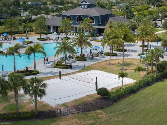 View of community featuring volleyball court, a swimming pool, fence, a lawn, and a patio