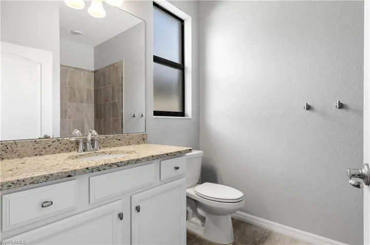 Full bath featuring baseboards, toilet, vanity, and wood finished floors