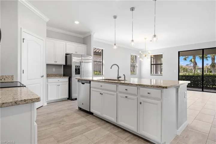 Kitchen with stainless steel appliances, a sink, an inviting chandelier, white cabinetry, and crown molding