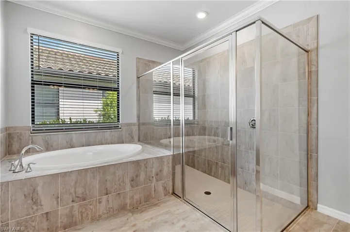 Bathroom featuring a bath, a shower stall, a wealth of natural light, and ornamental molding